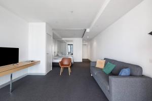 墨尔本Flinders Street Simplicity Overlooking the Yarra的带沙发、电视和床的客厅