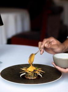 波尔多洲际波尔多格兰德酒店的用勺子在盘子上放碗的人