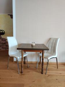 ForsternFestl Apartments - Nähe Messe München, Therme Erding的一张木桌,四周摆放着两把白色椅子