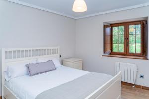 SobarzoLa Casita Verde de Cabárceno的白色的卧室设有一张白色大床和一个窗户。