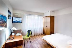 比尔City Hotel Biel Bienne Free Parking的酒店客房配有一张床、一张书桌、一张床和一张书桌。