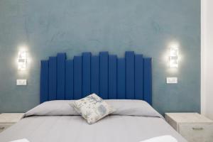 圣雷莫AFFITTACAMERE ELENA的一间卧室设有蓝色的墙壁和一张带枕头的床
