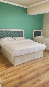 阿拉木图Khan Plaza的卧室配有白色的床和绿色的墙壁