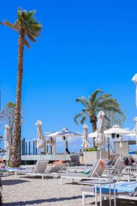 伏罗拉Belvedere Hotel的海滩上的一组椅子和遮阳伞