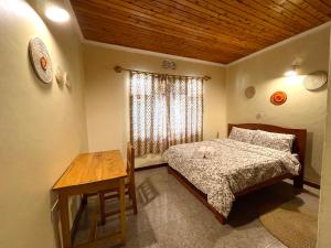 阿鲁沙Toiwo Residence Arusha的一间卧室配有一张床、一张桌子和一个窗户。