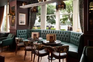 安布尔塞德The Waterhead Inn- The Inn Collection Group的一间带两张桌子和一张绿色沙发的餐厅