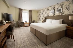 安布尔塞德The Waterhead Inn- The Inn Collection Group的酒店客房设有一张大床和一张书桌。
