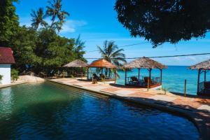 刁曼岛Japamala Resort by Samadhi - Adults Only的毗邻大海的带椅子和遮阳伞的游泳池