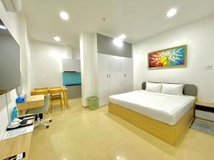 胡志明市Chanh Huy Apartments & Hotel的一间卧室配有一张床铺和一张桌子,还设有一间厨房
