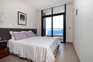 贝尼多姆Luxury apartment Residencial Sunset Drive - Benidorm, España的一间卧室配有带粉红色枕头的床和窗户。