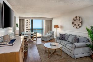 大洋城Ashore Resort & Beach Club的客厅配有沙发和桌子