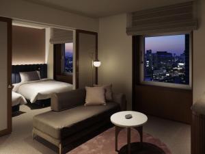 埼玉市The Mark Grand Hotel的酒店客房设有沙发、床和窗户。