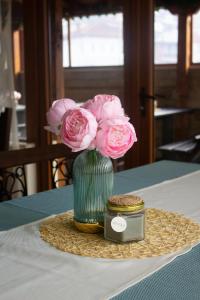 切佩拉雷米特奥家庭酒店的绿花瓶,桌子上放着粉红色的花