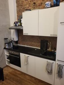 安特卫普Cosy Homestay的厨房配有白色橱柜和黑炉灶烤箱。