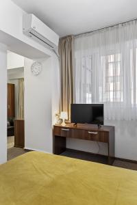 布加勒斯特Lina Hotel的一间卧室配有一张床和一张书桌及电视