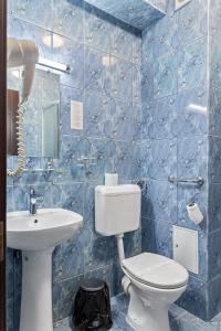 布加勒斯特Lina Hotel的蓝色瓷砖浴室设有卫生间和水槽