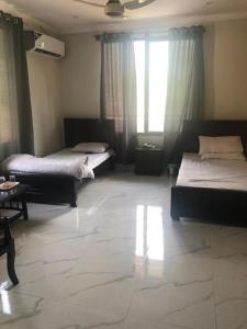 穆扎法拉巴德Hotel La Orilla Muzaffarabad的一间卧室设有两张床和大窗户