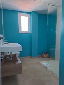 皮内达德马尔Bamblue Boutique Apartments的浴室设有蓝色的墙壁、水槽和淋浴。