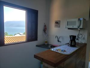 伊利亚贝拉Chalé & Suítes Mar Aberto的厨房设有窗户,在柜台上配有咖啡壶