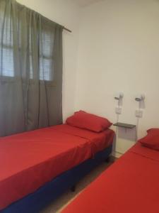 萨尔塔Pachá Hostel Backpack的宿舍间的两张床,配有红色床单和窗户