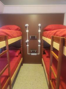 萨尔塔Pachá Hostel Backpack的一间卧室配有两张双层床,铺有红色床单