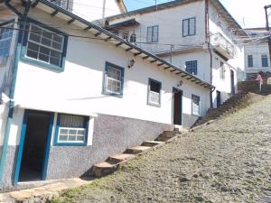 欧鲁普雷图Suíte Charmosa em Hospedaria no Centro的白色的房子,设有蓝色的门和楼梯