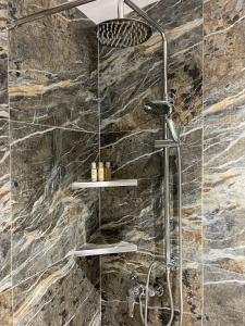 都拉斯SOL INVICTUS Boutique Hotel Durres Albania的带淋浴的浴室(带石墙)