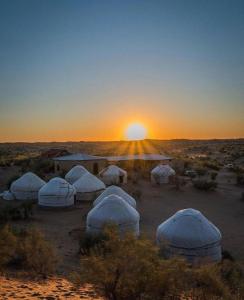 NurotaKyzylkum Nights Camp & Family Yurt的日落时分沙漠中的一组圆顶
