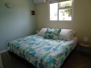 努尔德Pura Vida Aruba appartement Cama的一间卧室配有一张带五颜六色的被子的床和窗户