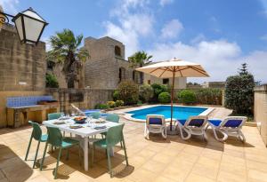 加斯利Dar ta' Lonza Villa with Private Pool的庭院配有桌椅和遮阳伞。