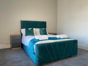 米德尔斯伯勒Entire Modern Home Middlesbrough的一间卧室配有一张大床和绿色床头板
