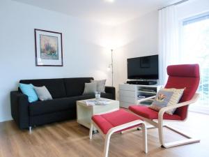 赛巴特班森Strandoase - FeWo 21的带沙发和红色椅子的客厅