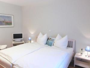 赛巴特班森Strandoase - FeWo 21的卧室配有白色的床和电视。