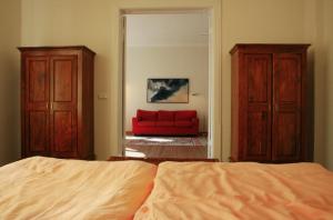 科尔平塞Villa Daheim - FeWo 02的一间卧室配有一张床和一张红色的沙发