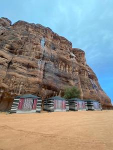 瓦迪拉姆Shahrazad desert, Wadi Rum的岩石墙旁海滩上的两张床