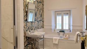 霍伊斯Simonstone Hall Hotel的一间带水槽、浴缸和镜子的浴室