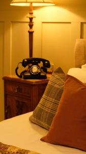 霍伊斯Simonstone Hall Hotel的一张桌子上的电话,床边
