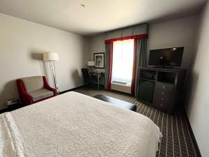 PearsallStudio 6 Suites Pearsall TX的酒店客房配有一张床、一台电视和一把椅子