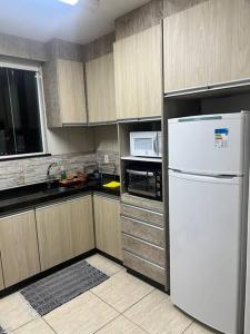 蓬塔格罗萨Ap Central c/ Garagem的厨房配有白色冰箱和微波炉