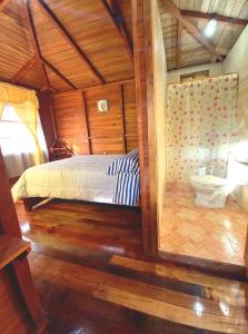 巴尼奥斯Paraiso Orquideario的一间卧室配有一张床,一间卫生间位于客房内