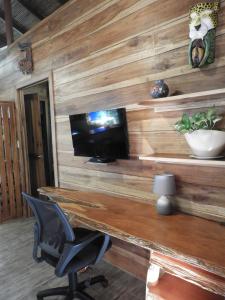 科克莱斯Casita Bribri at Margarita Hills的木墙,配有书桌、电视和椅子