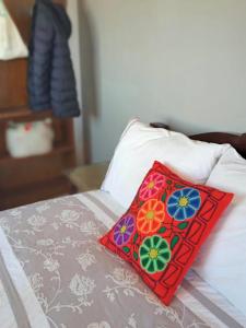 瓜伊马延Rodando x Mendoza的床上的红色枕头,上面有鲜花