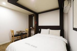 水原市Suwon Hotel Praha的卧室配有白色的床和桌子