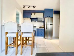 圣保罗Apartamento Espaçoso e Aconchegante na Bela Vista的厨房配有蓝色橱柜和2把白色椅子