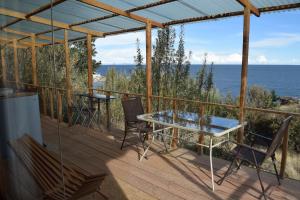 奥科苏尤Allpaluxe Peru Lodge的一个带桌椅的甲板和大海