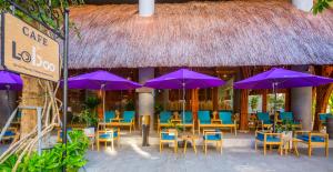 岘港阿凡达岘港酒店的一间设有紫色遮阳伞和桌椅的餐厅
