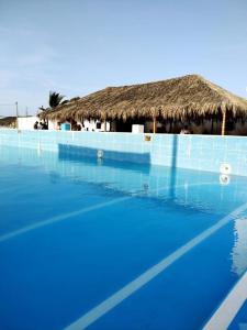 索里托斯Bamboleo Club Zorritos的蓝色的游泳池,带茅草屋顶