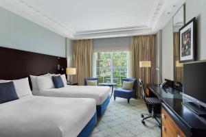 开罗Renaissance Cairo Mirage City Hotel的酒店客房设有两张床、一张桌子和一台电视。