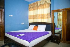 AtasomansoKiverly Guest House的一间卧室配有一张带紫色床单和镜子的床
