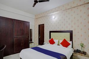 勒克瑙Shree Hotel的一间卧室配有一张带红色和蓝色枕头的床
